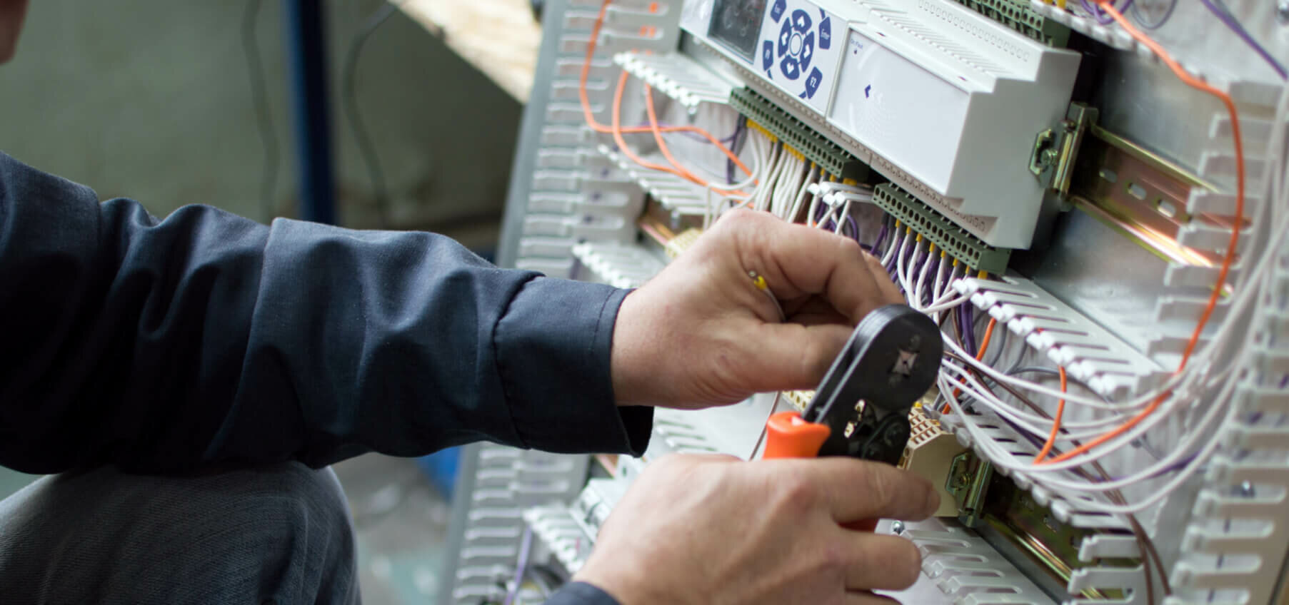 Electrician assembling industrial control cubicle in workshop. Close-up photo.